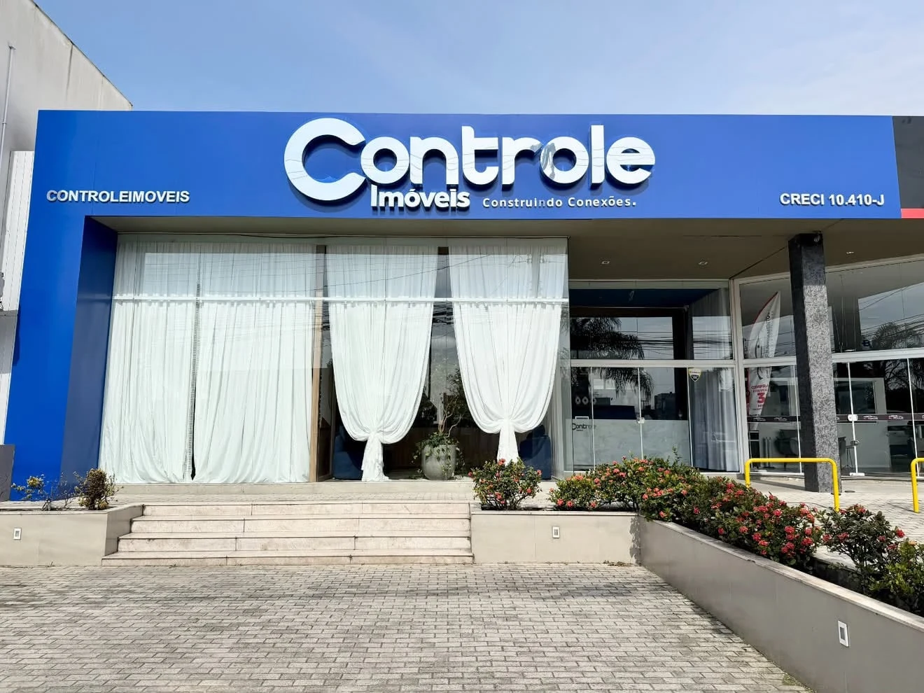 Fachada azul da Controle Imóveis com identificação em letras claras.