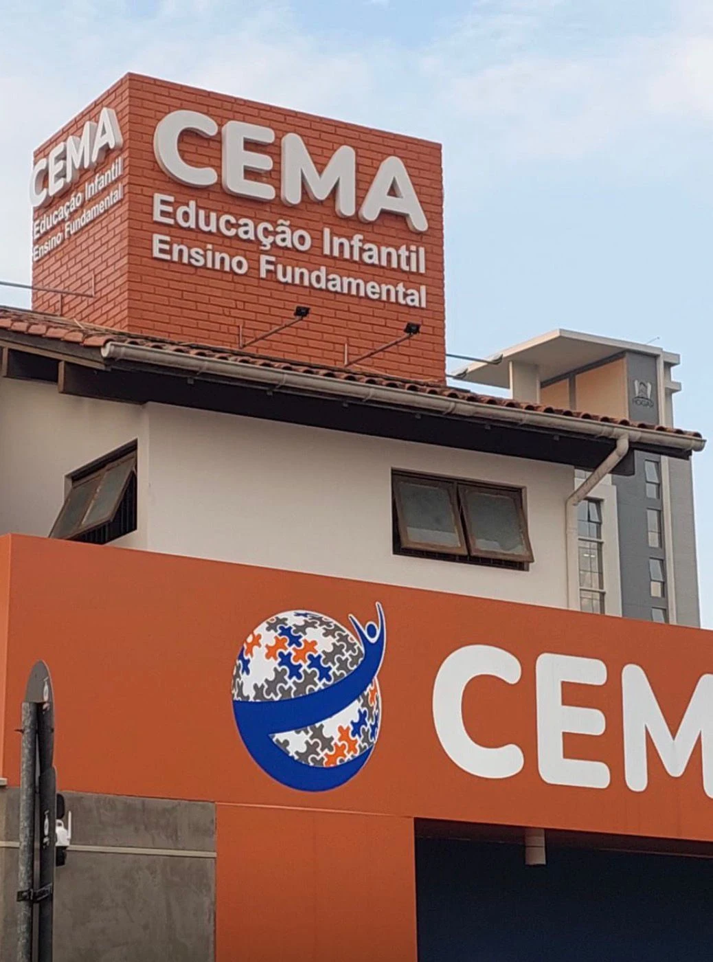 Fachada laranja do CEMA com identificação branca em relevo.