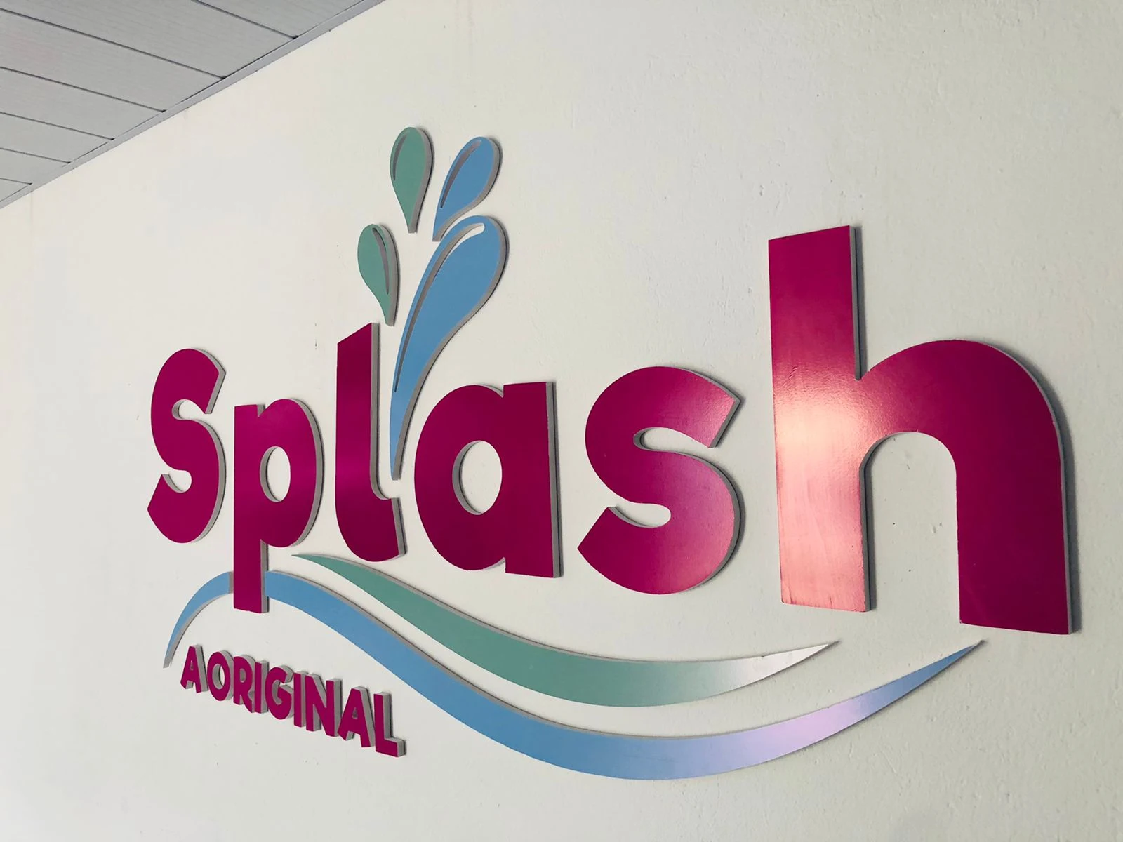 Letreiro Splash com letras coloridas em relevo sobre uma parede clara.